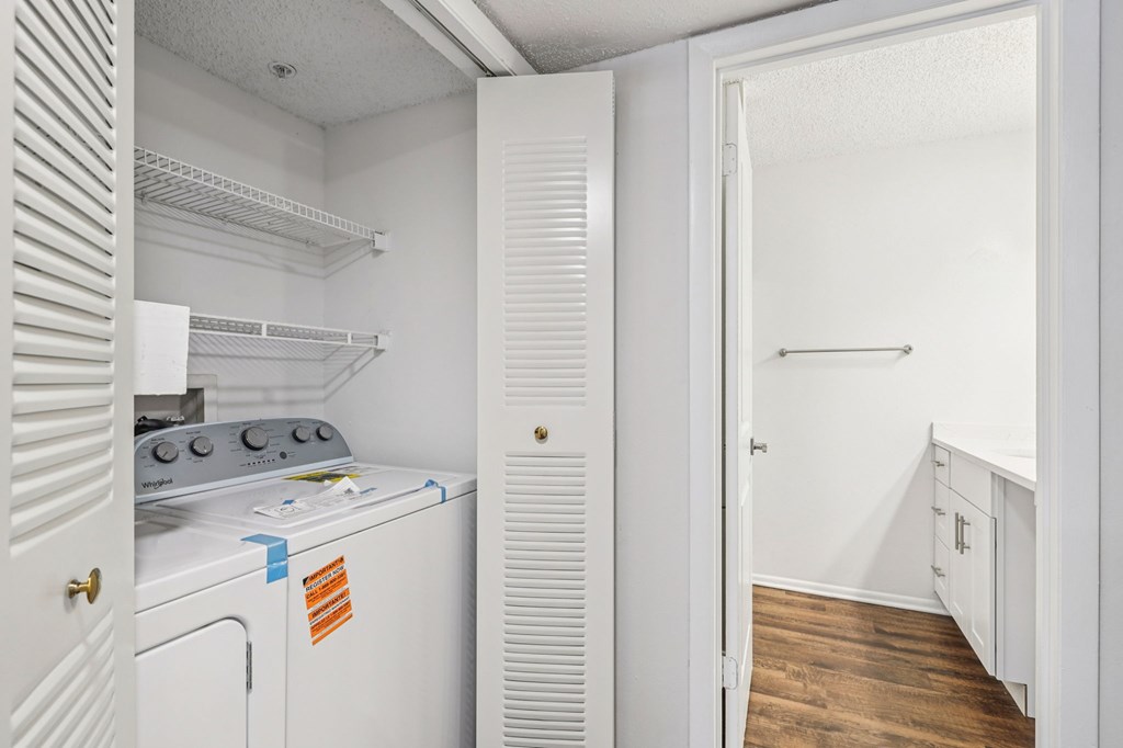 A white kitchen with a stove and a doorway leading to a hallway.