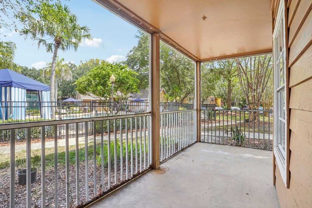 A patio with a metal railing and a view of a park.