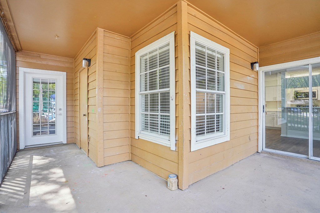 A sunny day at a wooden house with a white door and windows.