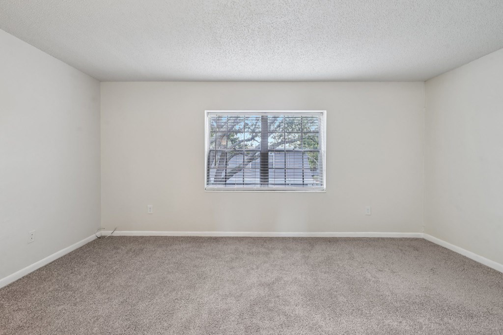 A room with a window and carpeted floor.