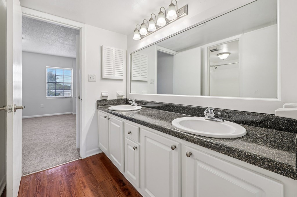 A bathroom with a sink, mirror, and wooden floors.