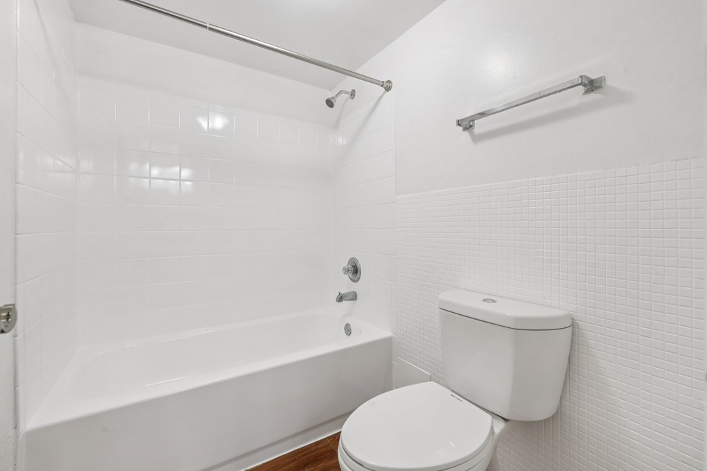 A white bathroom with a toilet, tub, and towel rack.