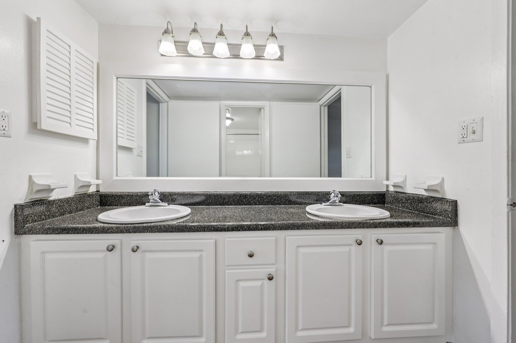 A bathroom with two sinks and a large mirror.