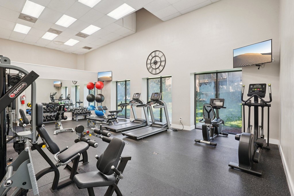 A spacious gym with a variety of equipment including treadmills, stationary bikes, and weight machines.