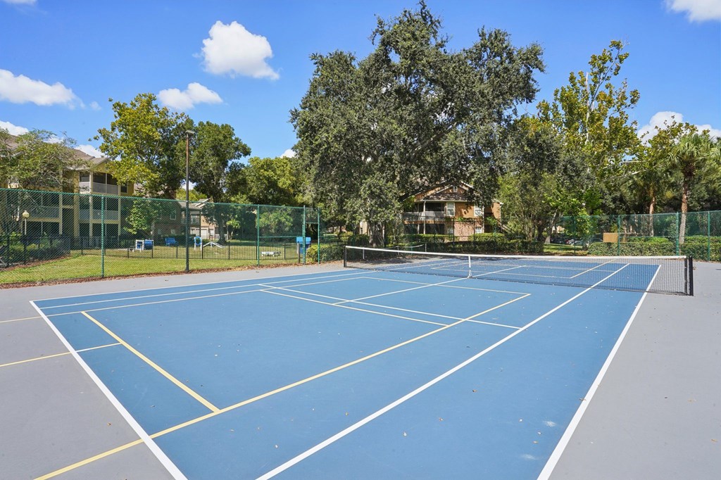 A tennis court surrounded by a fence and trees.