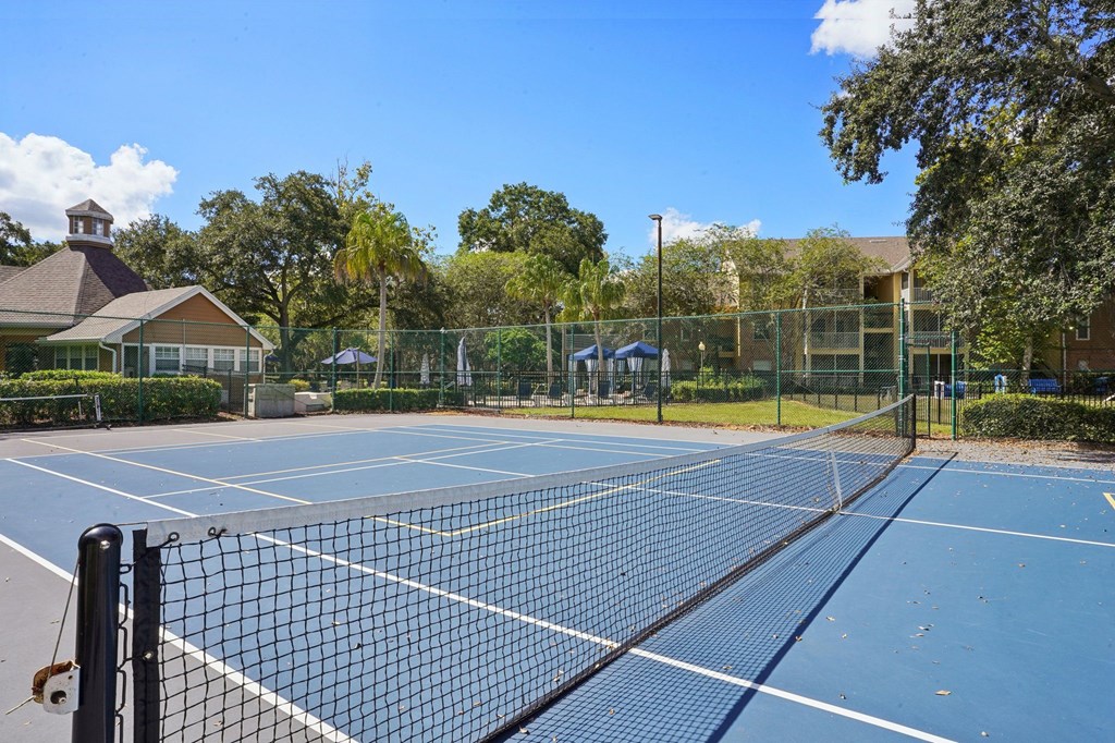 A tennis court with a black net and a building in the background.