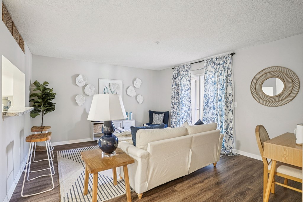A living room with a white couch, a wooden table, and a mirror on the wall.