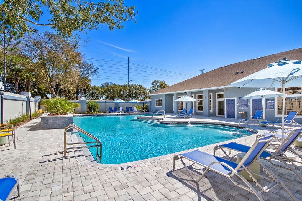 resort style swimming pool is in front of clubhouse with lounge chairs