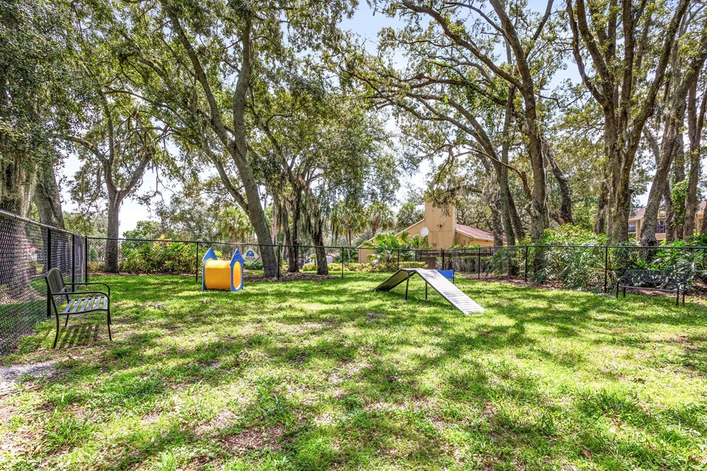 A playground with a slide and a swing set in a grassy area surrounded by trees.