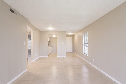 A spacious room with tiled flooring and white walls.