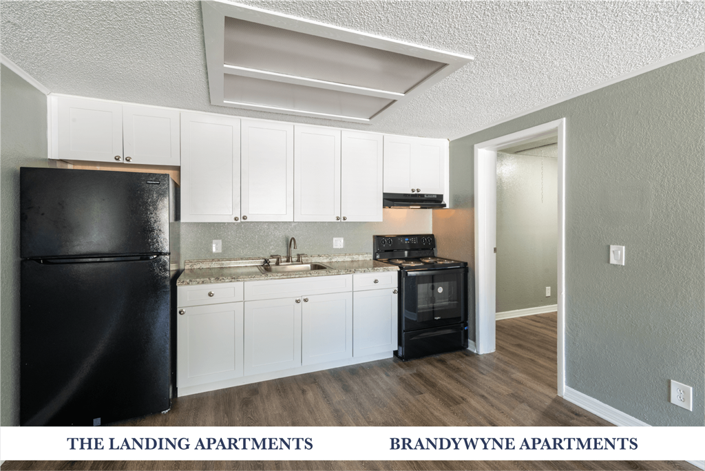 A kitchen with white cabinets and a black fridge.