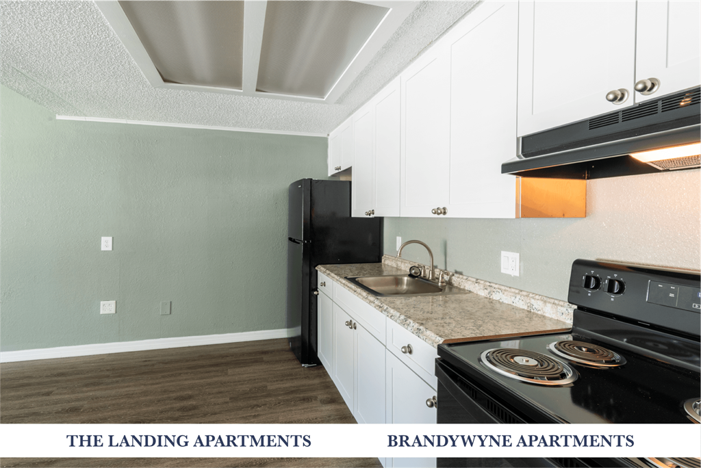 A kitchen with a black fridge and stove top oven.