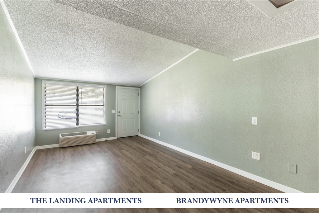 A sparsely furnished apartment with a window and a door.