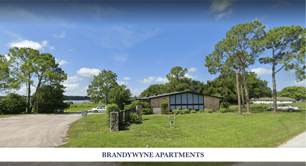 A sign for Brandywynne Apartments is displayed in front of a building surrounded by trees.