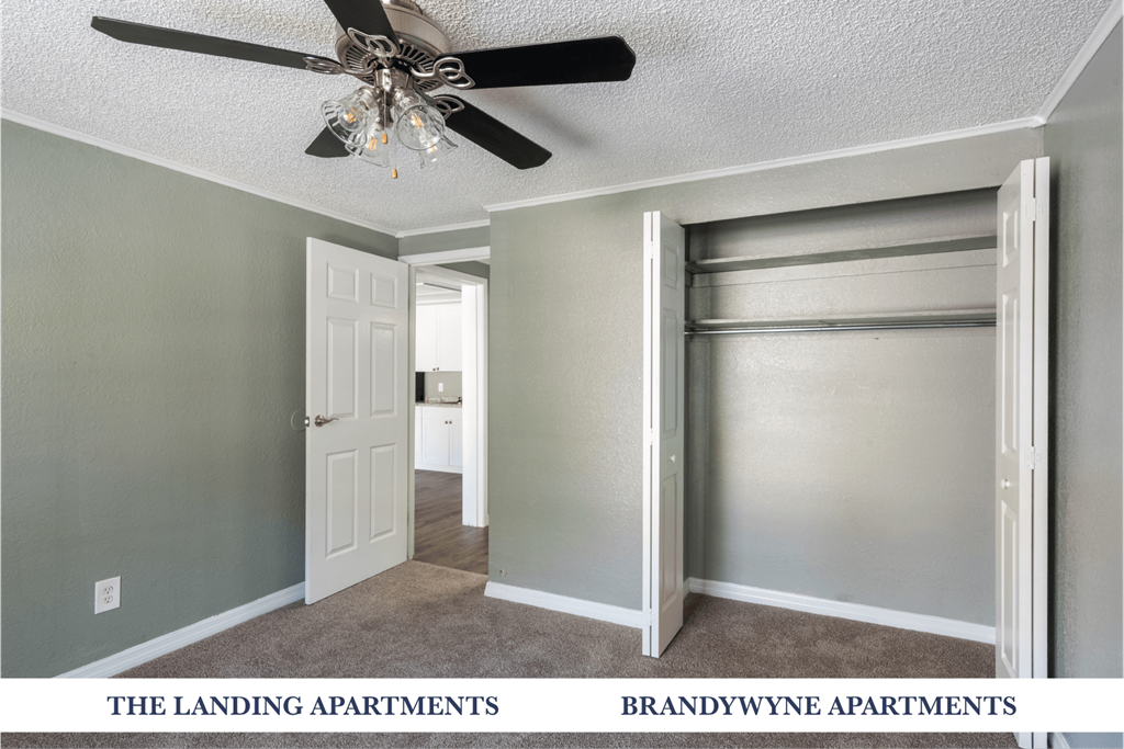 A room with a ceiling fan and a door leading to another room.