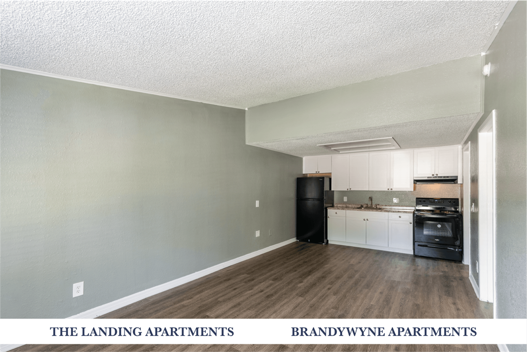A kitchen area with a black fridge and white cabinets.