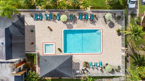 a birds eye view of the pool of a resort with umbrellas