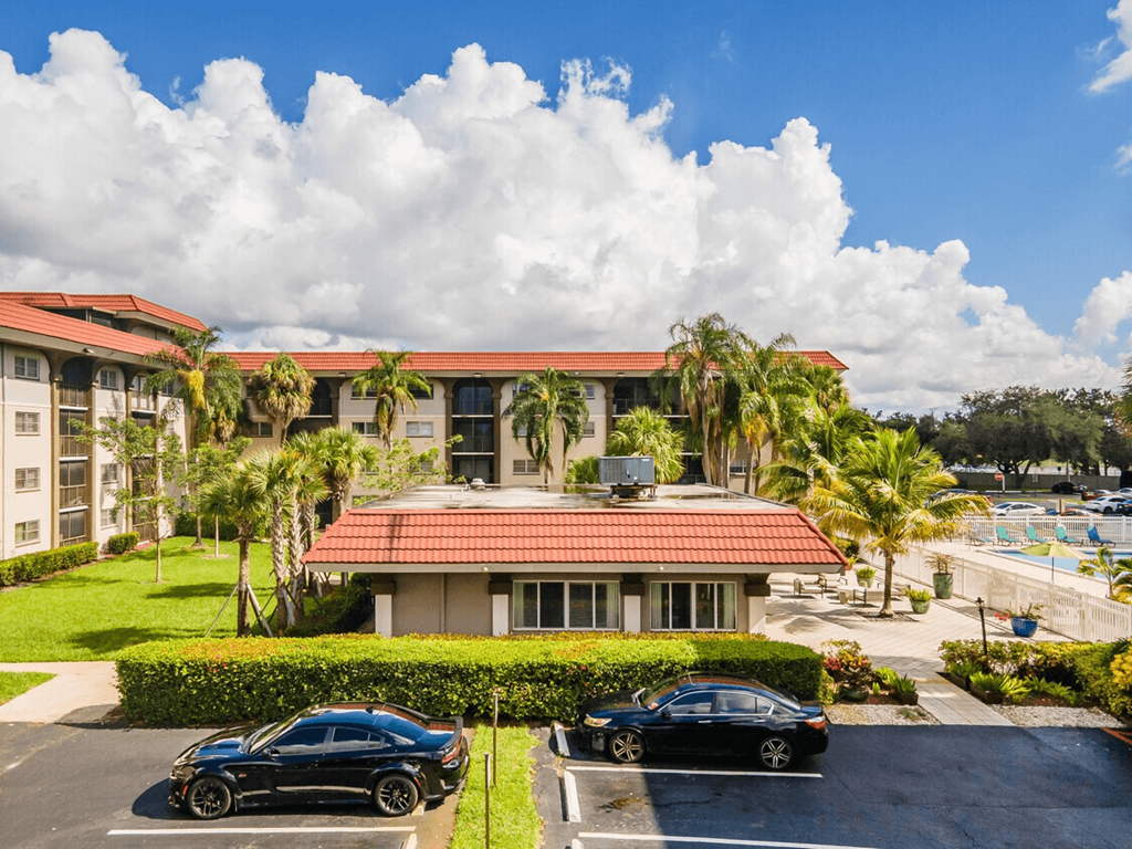 Two black cars parked in front of a building with a red roof.