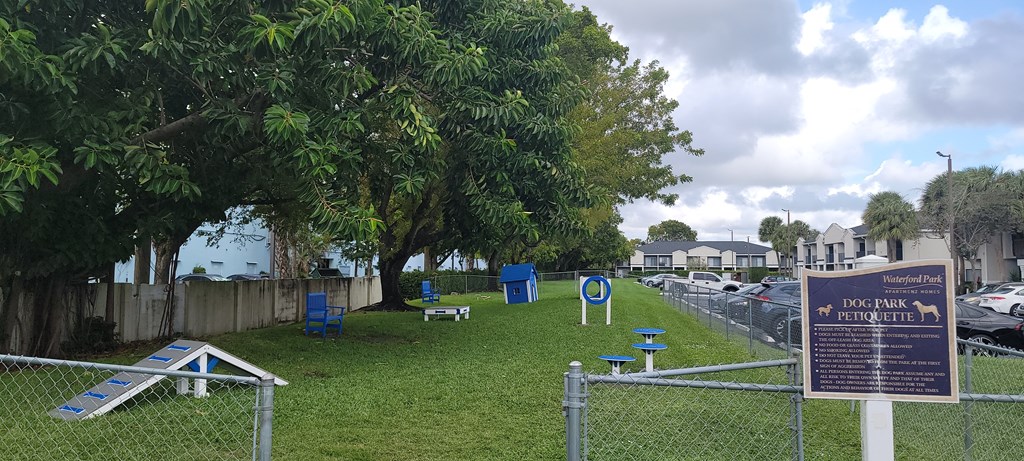 a park with a sign and chairs in the grass