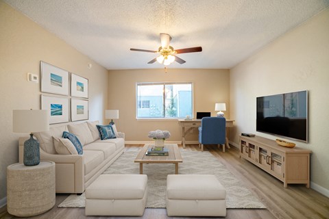 A living room with a white couch, a coffee table, and a flat screen TV.