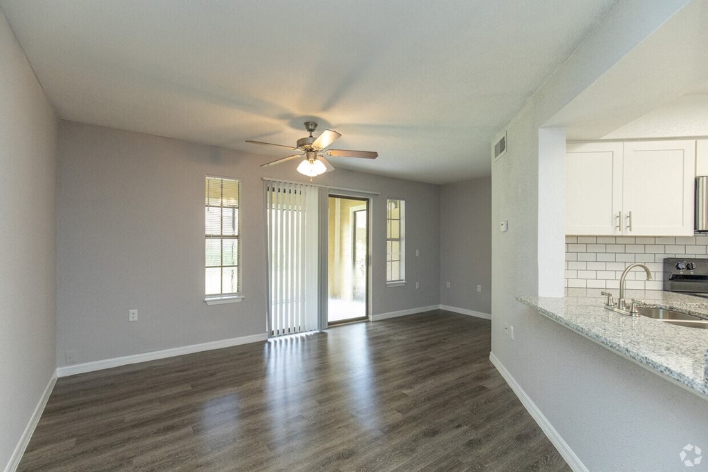 A spacious room with a ceiling fan and a kitchen area with a sink.