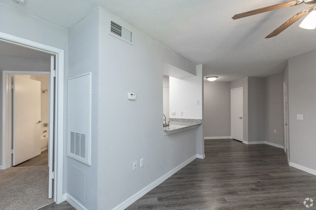 A spacious room with a ceiling fan and a doorway leading to another room.
