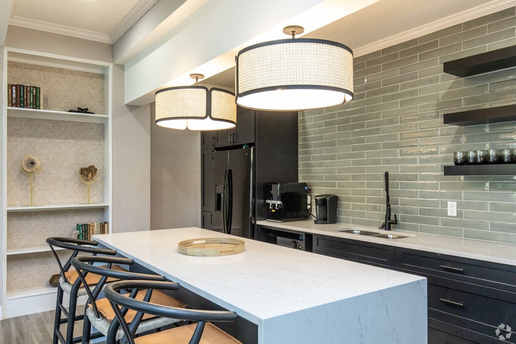 A kitchen with a white countertop and black chairs.