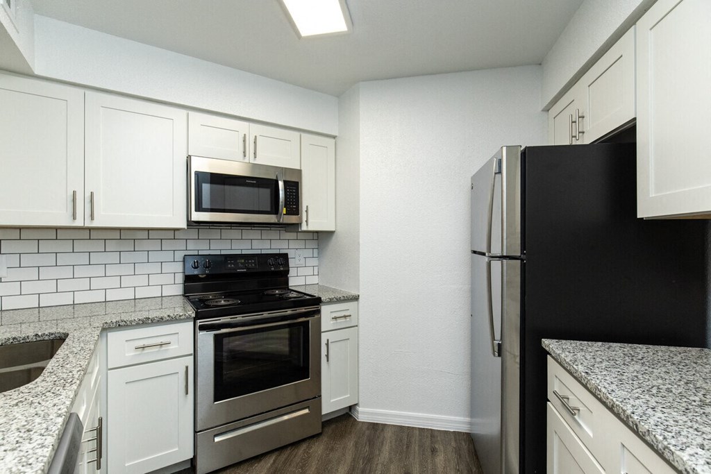 A kitchen with white cabinets and black appliances.