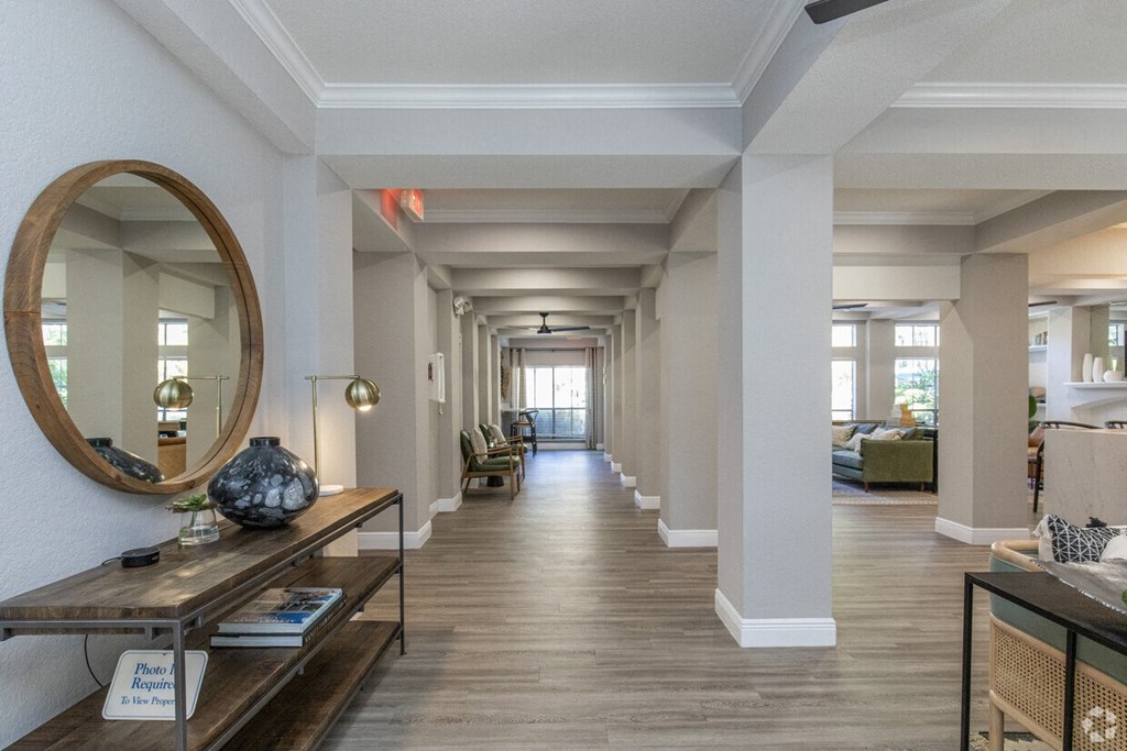 A long hallway with a round mirror on the wall.