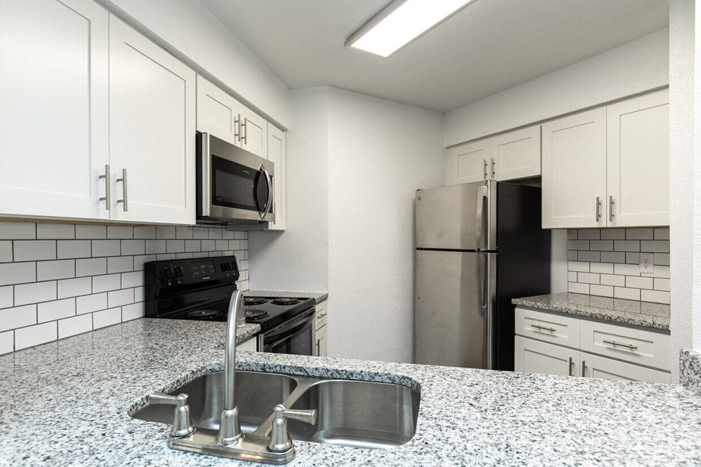 A kitchen with a sink, stove, and refrigerator.