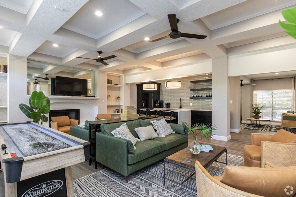 A living room with a pool table and a green couch.