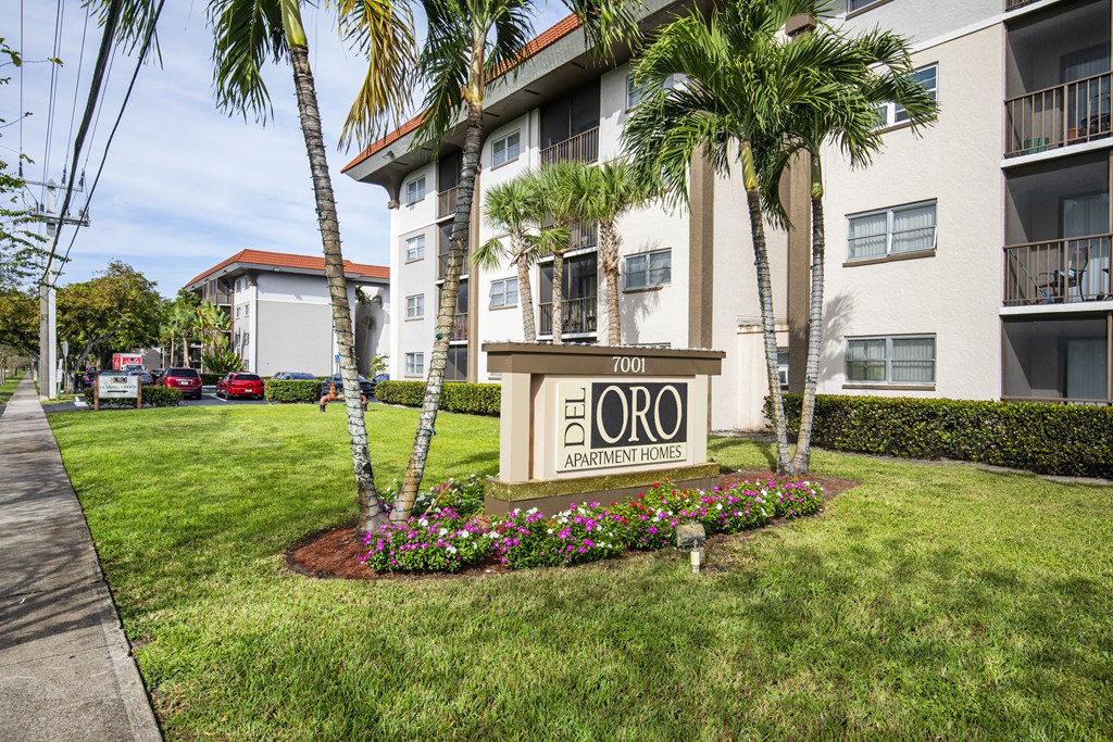 A sign for Del Oro Apartment Homes is in front of a building with a landscaped area.