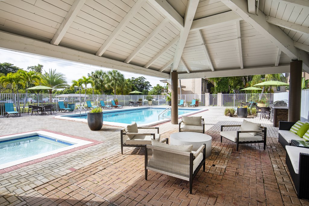 A patio with a pool and a white umbrella.