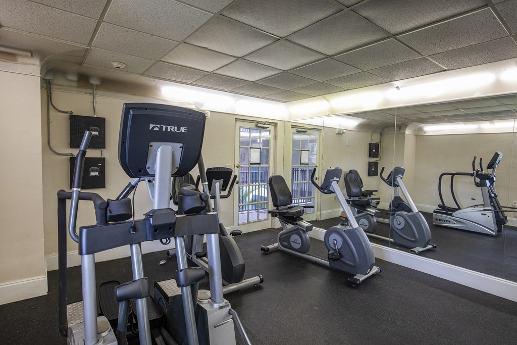 A gym with a variety of exercise equipment including treadmills, stationary bikes, and elliptical machines.
