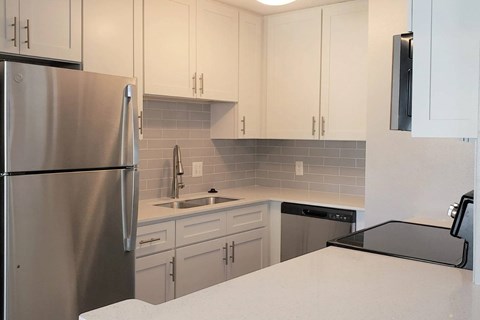 A kitchen with a stainless steel refrigerator and white cabinets.