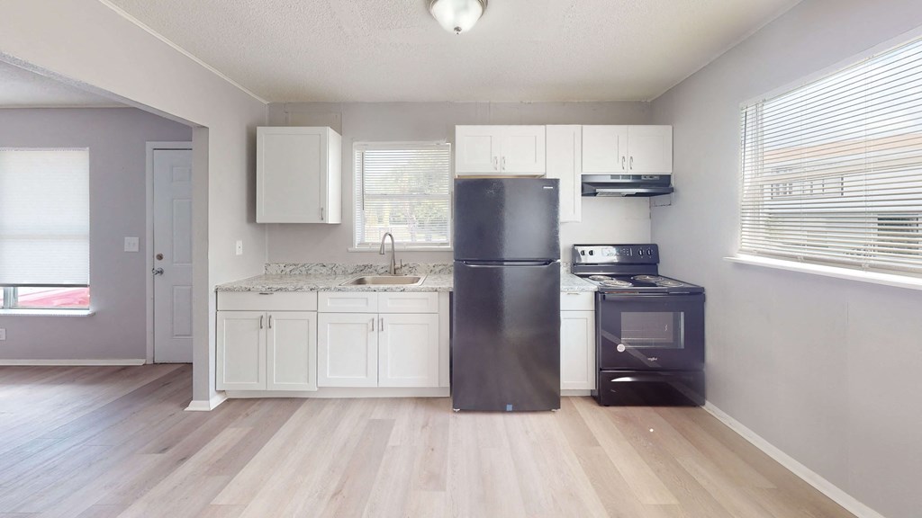a kitchen with white cabinets and a black refrigerator