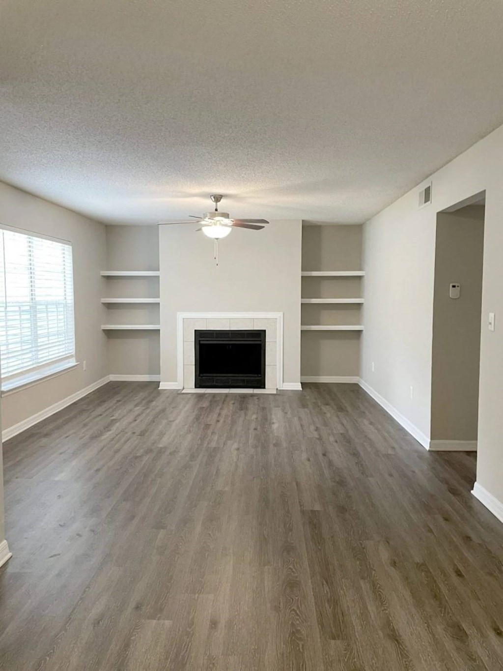 A room with a fireplace and shelves.