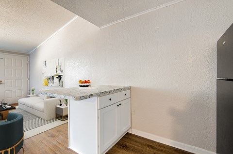 A kitchen with white cabinets and a marble island.