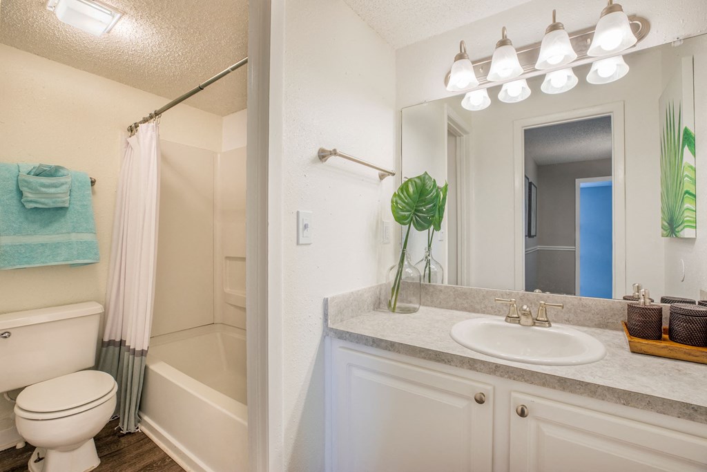 A bathroom with a white toilet, a white sink, and a white bathtub with a blue towel on the towel rack.