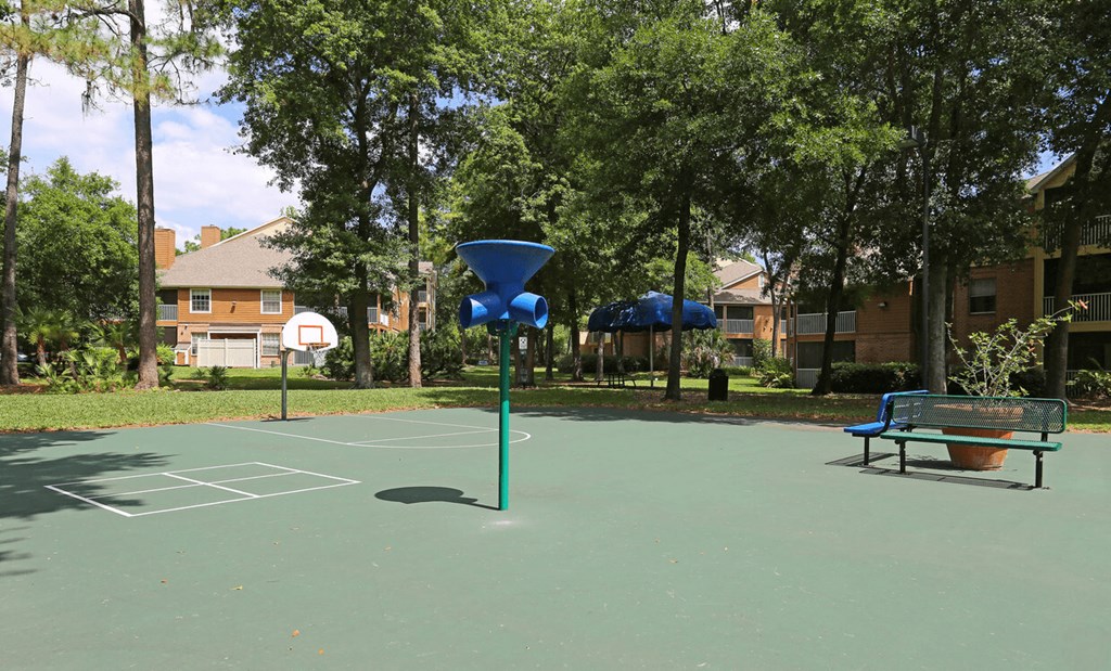 A basketball court with a blue hoop and a bench.