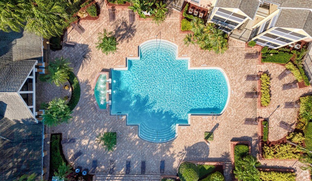 A swimming pool surrounded by a stone patio and landscaping.