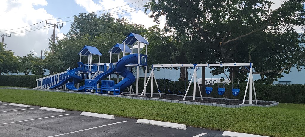 a playground with a blue slide in a parking lot