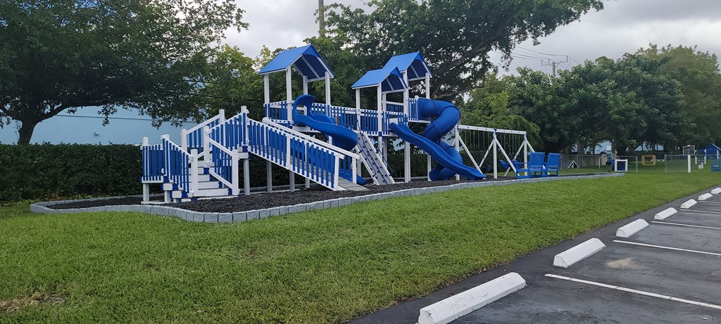 a playground with a blue set of slides in a parking lot