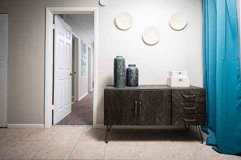 a hallway with a dresser and a door to a room with blue curtains at Fairways of Inverrary, Lauderhill, FL, 33319