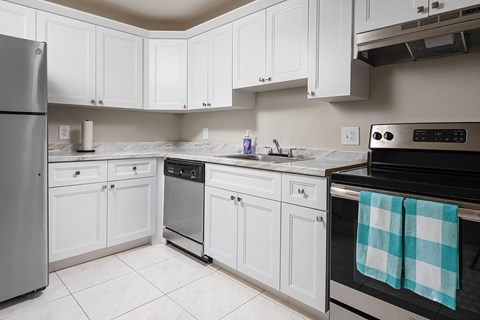 a kitchen with white cabinets and black and silver appliances at Fairways of Inverrary, Lauderhill, FL