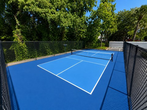 A blue tennis court surrounded by a fence.