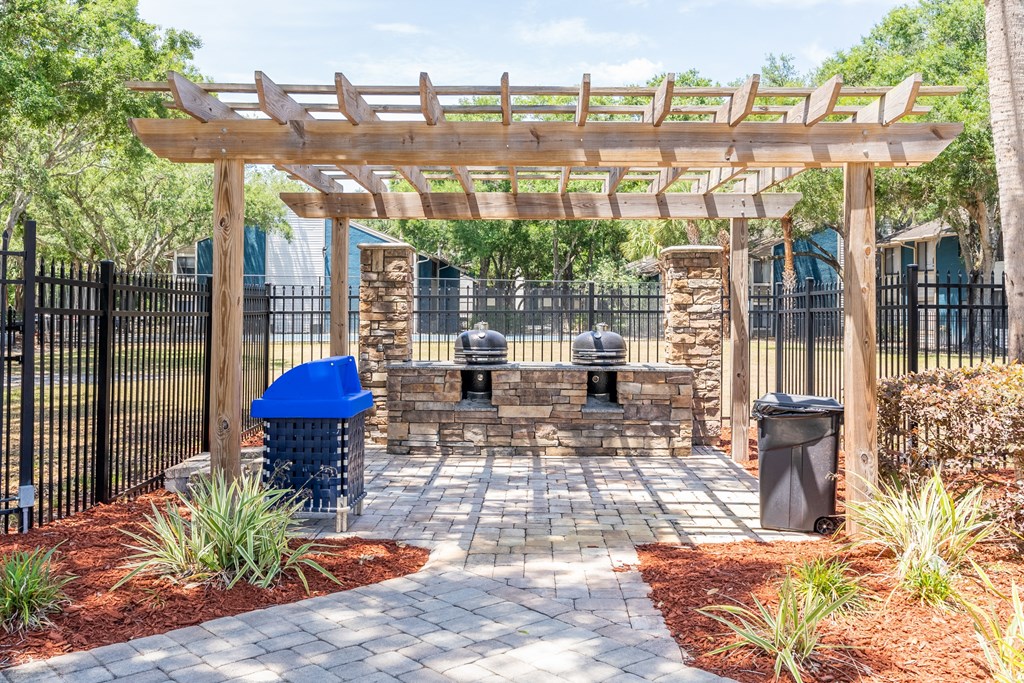 a patio with a stone fireplace and a wooden pergola  at Fisherman's Landing Apartment Homes, Tampa, Florida