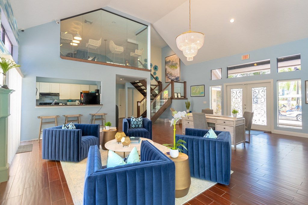 a living room with blue couches and chairs and a kitchen  at Fisherman's Landing Apartment Homes, Tampa, FL