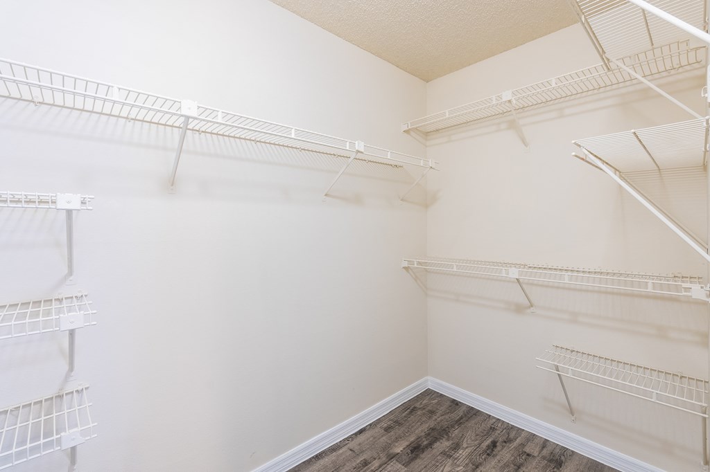 a spacious walk in closet with white walls and shelves and mirrored closet doors a spacious walk in closet with white walls and shelves and mirrored closet doors at Fisherman's Landing Apartment Homes, Tampa, Florida