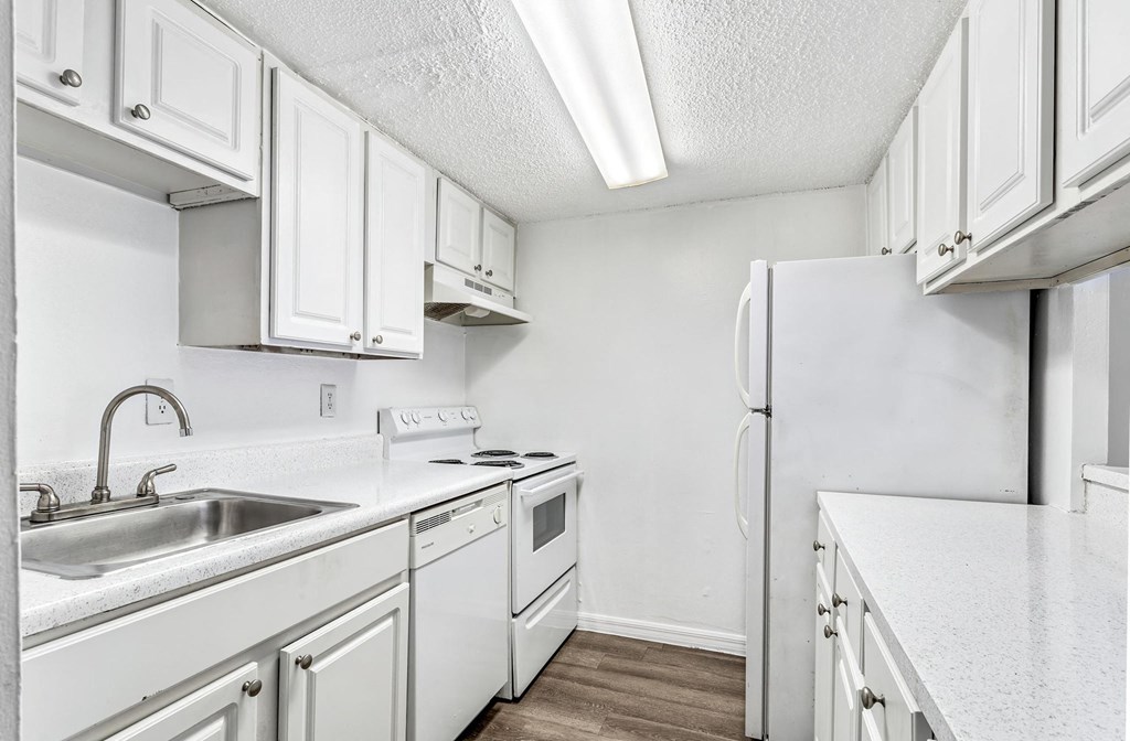 a kitchen with white cabinets and a sink and a refrigerator at Greenwich Commons Apartment Homes, Tampa, FL, 33613